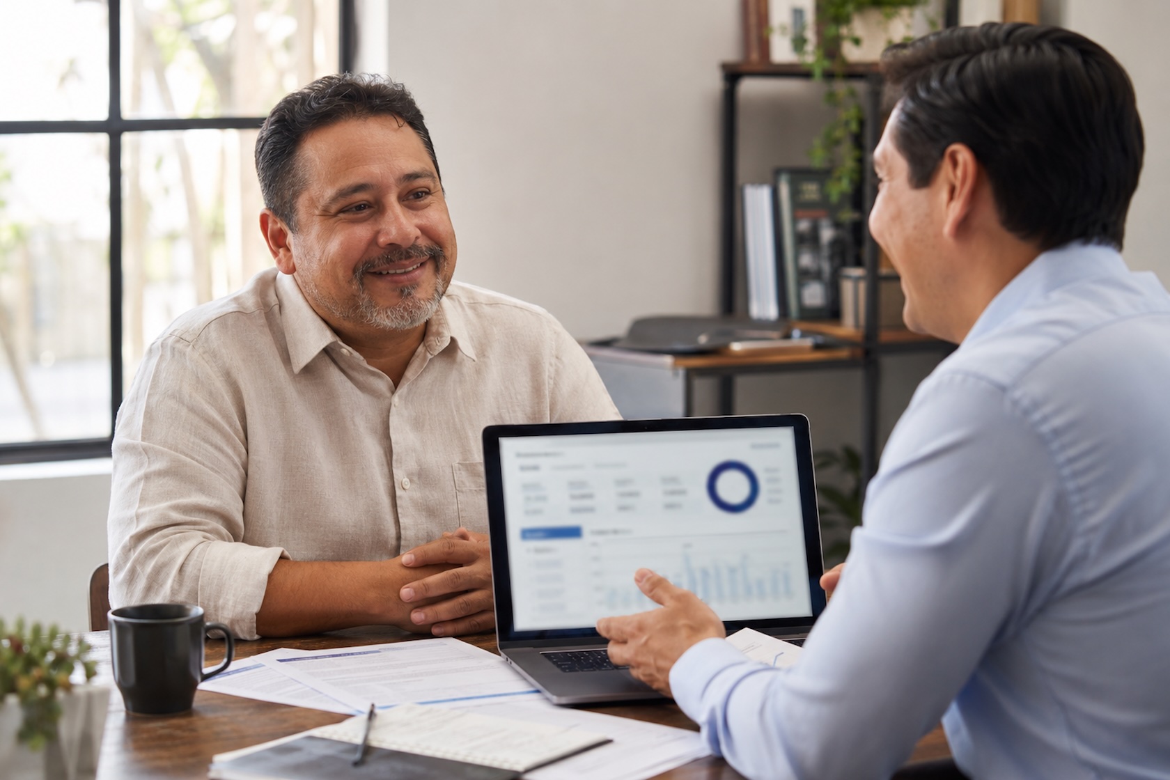 Small business owner and advisor reviewing business funding approval together on a laptop