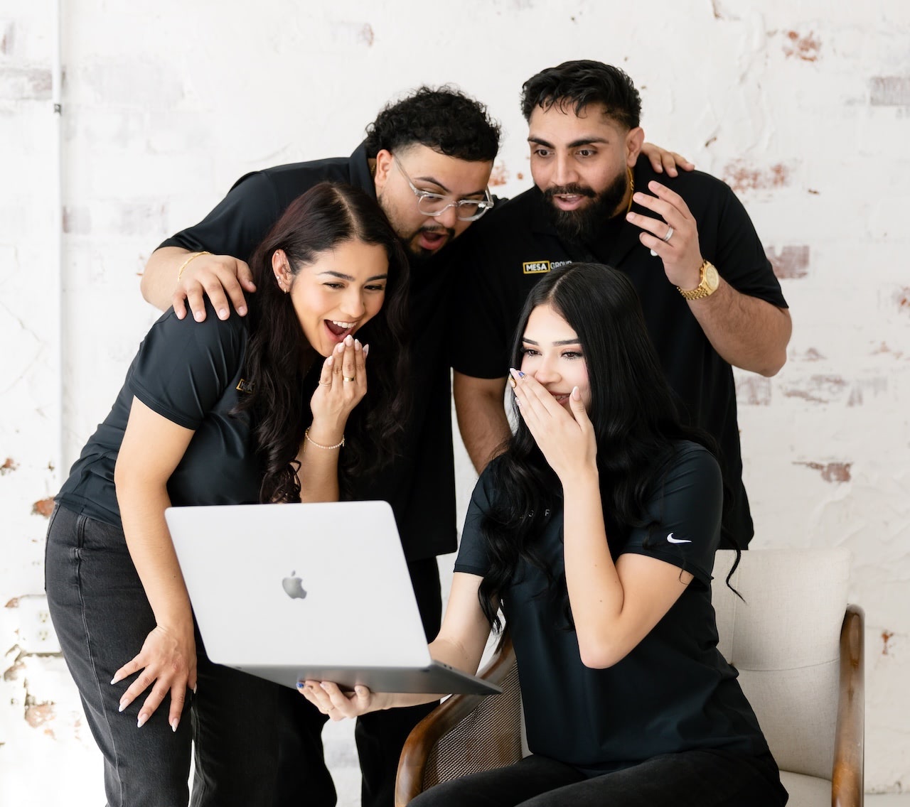 Mesa Group Consulting team gathered around a laptop celebrating a client win